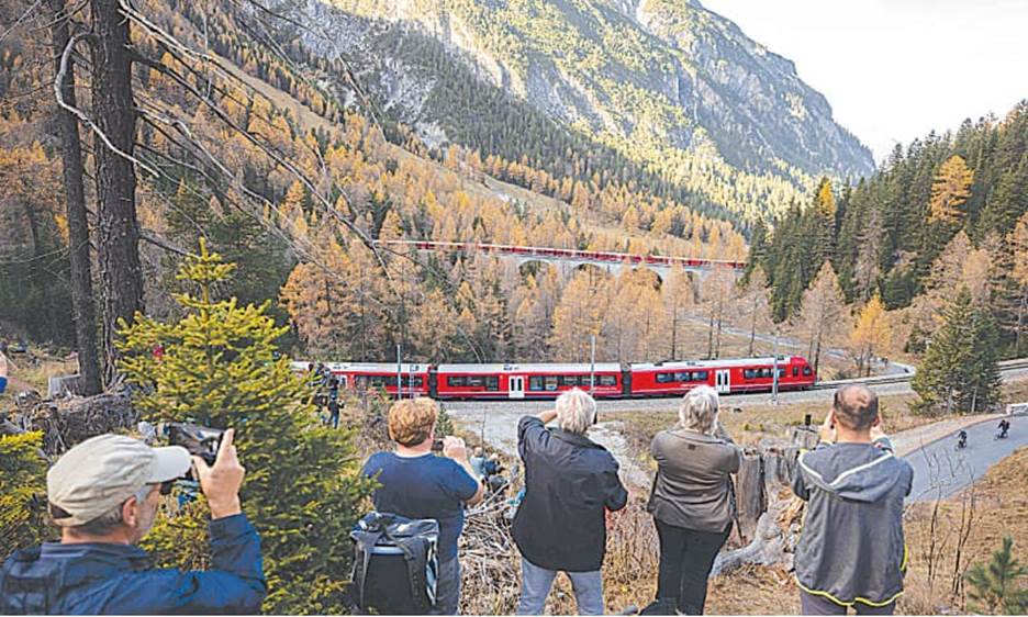 TOURISTS capture images as a 1,910-metre-long train with 100 cars passes near Bergun, on Saturday, during a record attempt, to mark the Swiss railway operator’s 175th anniversary.—AFP