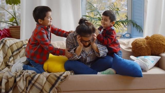 A person sitting on a couch with two boys  Description automatically generated
