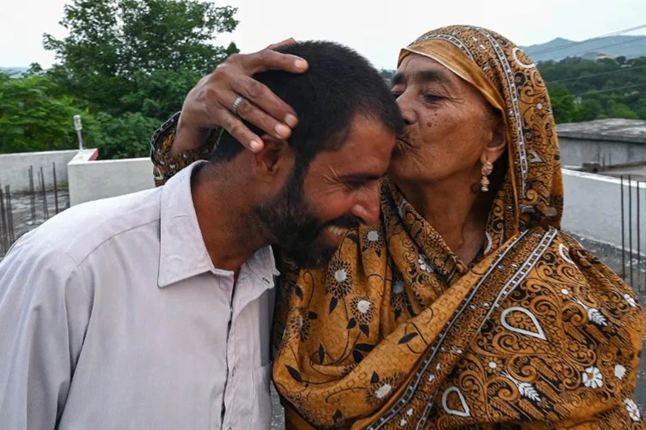 Muhammad Naeem Butt, who gave up on a perilous attempt to reach Europe, is kissed by his mother Razia Latif at their home in Pakistan (Aamir QURESHI)