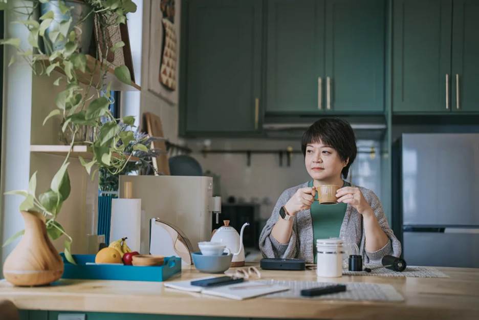 A young woman drinking coffee in her kitchen