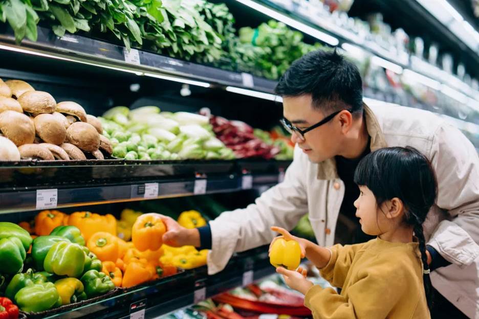 A father and daughter looking at produce in a grocery store