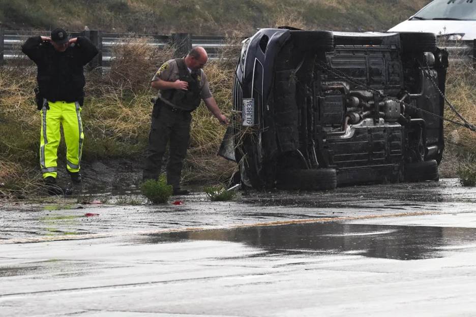 Emergency personnel look at a vehicle that flipped during a storm  (Patrick T. Fallon / AFP via Getty Images)