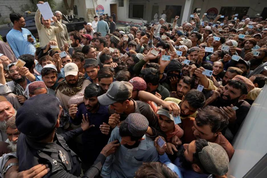 Police officers try to control immigrants, mostly Afghans, gather to verify their data at a counter of Pakistan's National Database and Registration Authority, in Karachi, Pakistan, Tuesday, Nov. 7, 2023. Pakistan government launched a crackdown on migrants living in the country illegally as a part of the new measure which mainly target all undocumented or unregistered foreigners. (AP Photo/Fareed Khan)