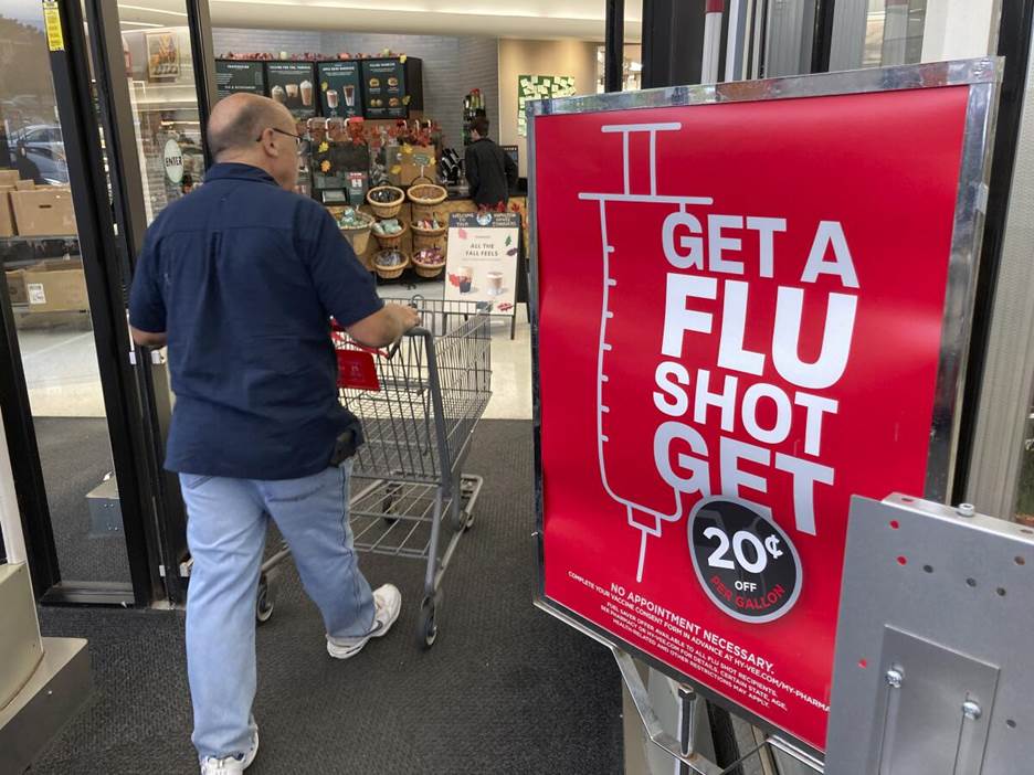 A shopper passes a sign urging people to get a flu shot.
