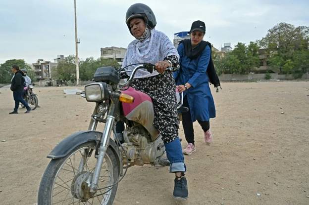 Zainab Safdar (R), an instructor with the women-only 'Rowdy Riders', assists a student during a lesson in Karachi (Asif HASSAN)