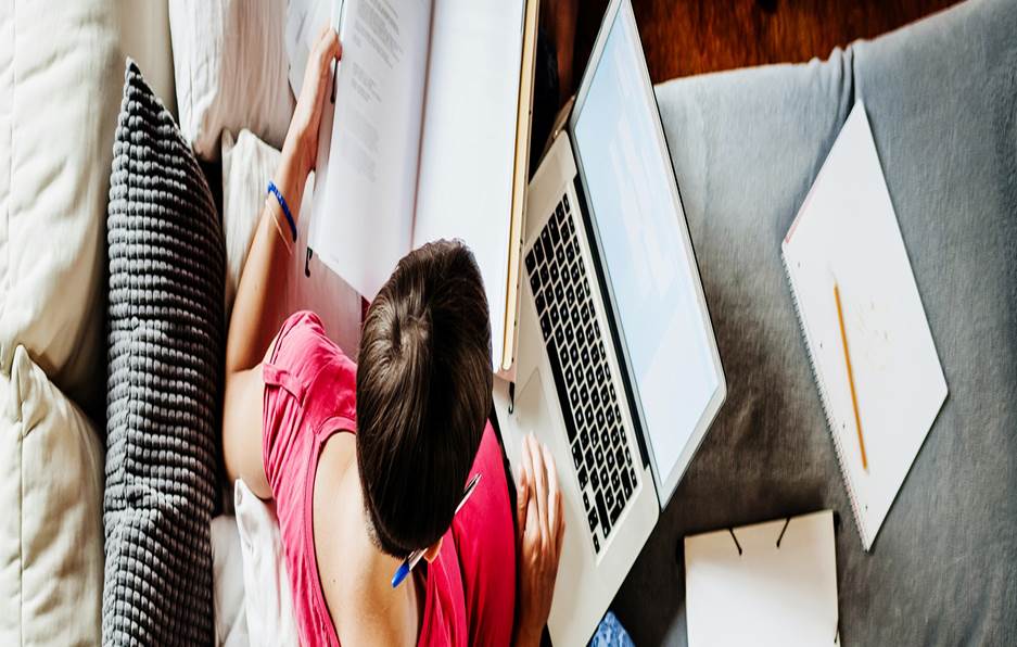 Person multitasking with laptop and notebook