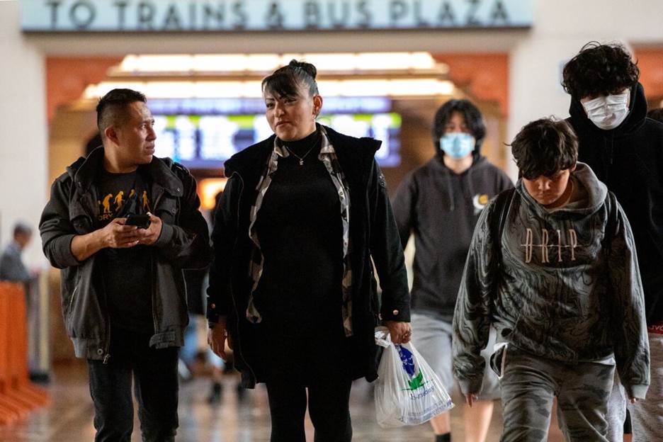 Commuters with and without face masks walk through Union Station.