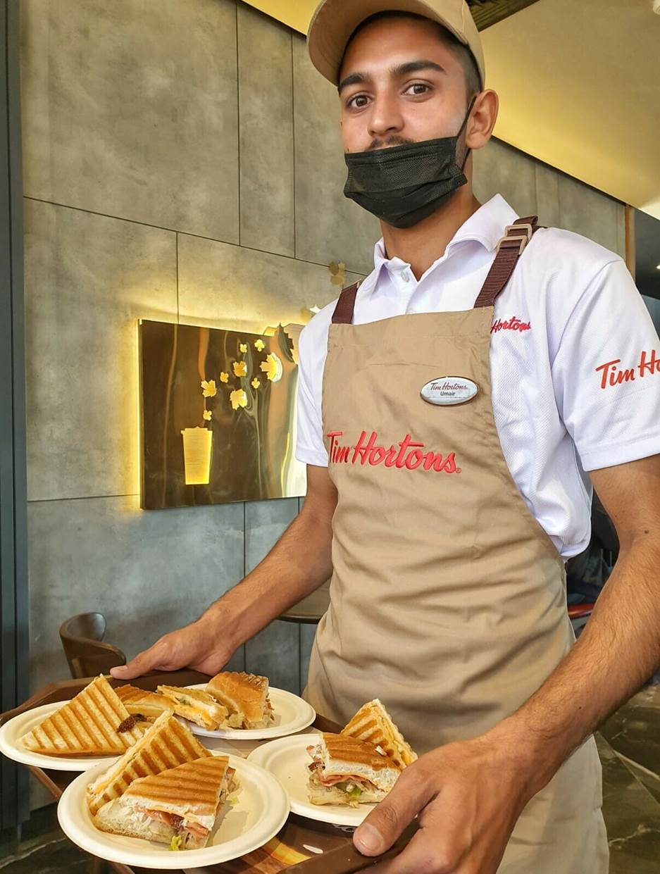 A chef holding a plate of food  Description automatically generated with medium confidence