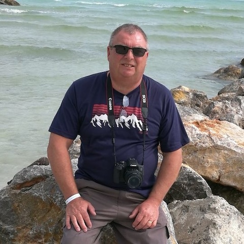 A person sitting on rocks by the water Description automatically generated with low confidence