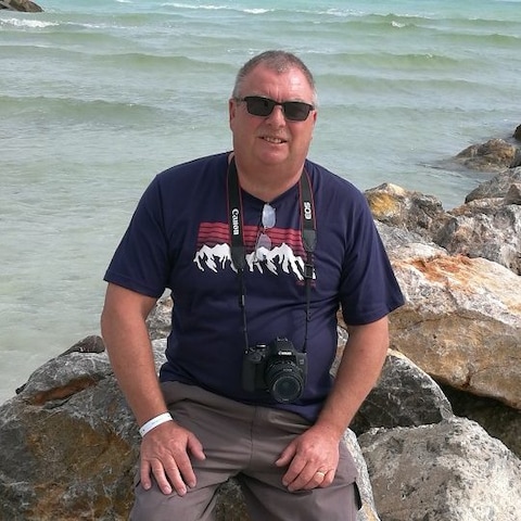 A person sitting on rocks by the water  Description automatically generated with low confidence