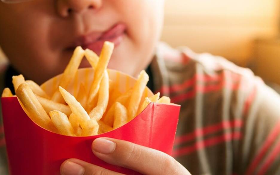 Cropped Image Of Tempted Boy Holding French Fries Packet