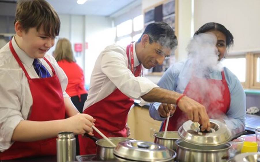 A group of people cooking in a kitchen Description automatically generated