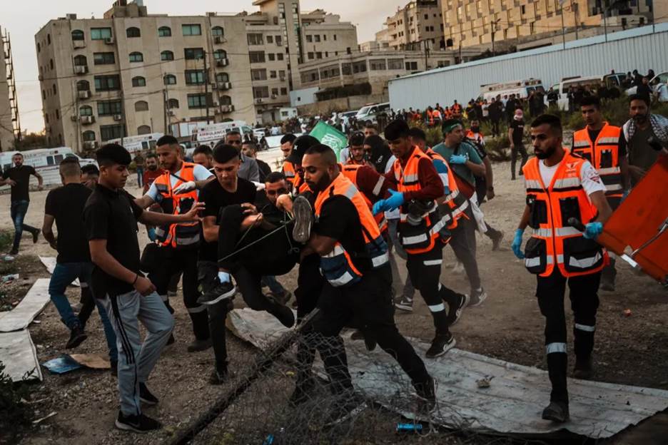 Paramedics carry a wounded Palestinian protester toward the ambulance after he was shot by Israeli forces.