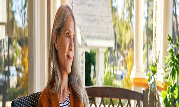 Smiling woman sits on front porch