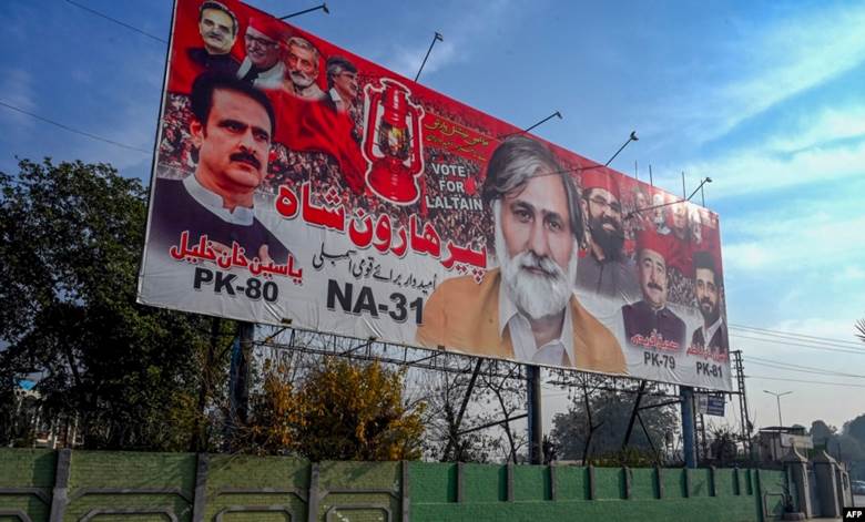 A car passes by an election billboard, ahead of Pakistan's general elections, along a road in Peshawar on Dec. 22, 2023.