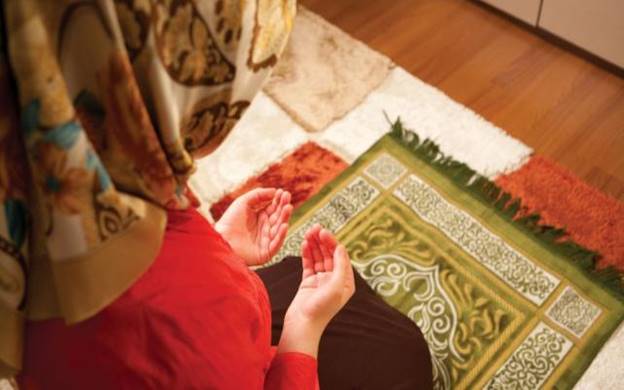 A person in a red shirt and a scarf praying Description automatically generated