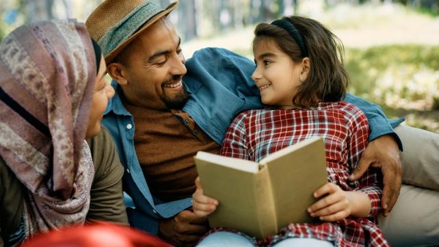 A person and a child reading a book Description automatically generated