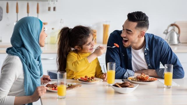 A person feeding a child to a person Description automatically generated