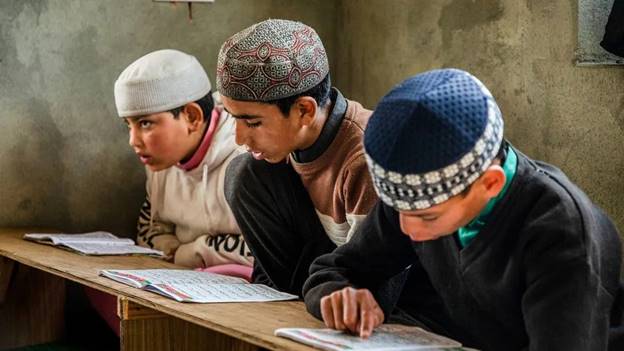 A group of boys sitting at a desk  Description automatically generated