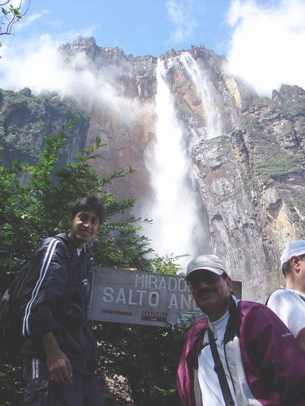 A group of men standing in front of a waterfall Description automatically generated