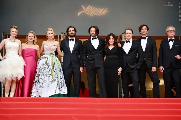 A group of people standing on a red carpet Description automatically generated