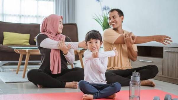 A group of people sitting on the floor with their hands on their head Description automatically generated