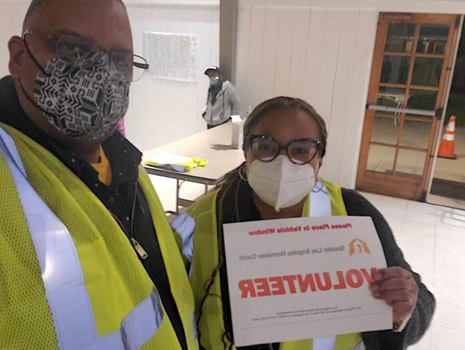 A person and person wearing masks and holding a sign  Description automatically generated with low confidence