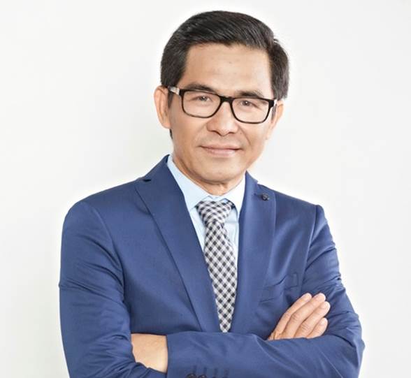 A person wearing glasses and a blue suit with his arms crossed  Description automatically generated with medium confidence