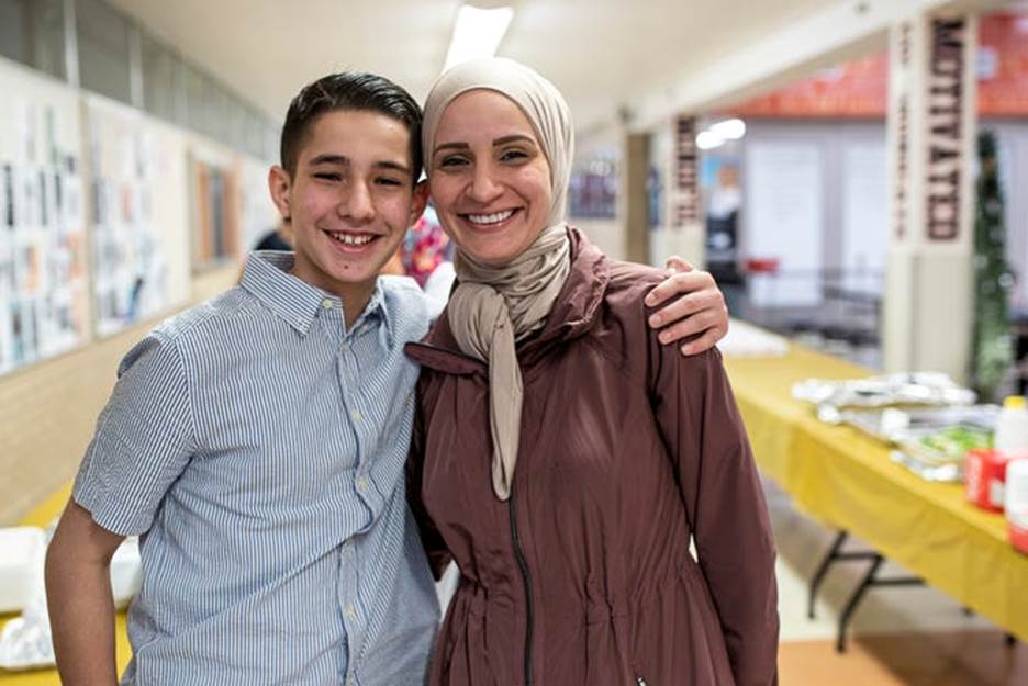 Co-organizer of the Iftar dinner Mohamad Sobh, 15, and his mother Reem Sobh pose for a photo during an iftar dinner at Dearborn High School in Dearborn on Thursday, April 21, 2022.