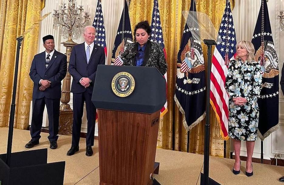 A group of people standing behind a podium with flags behind them Description automatically generated with low confidence