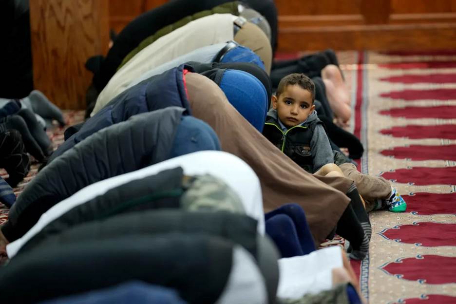 A boy is shown beside men praying, in Omar Mosque, in Paterson, Sunday, April 9, 2023.