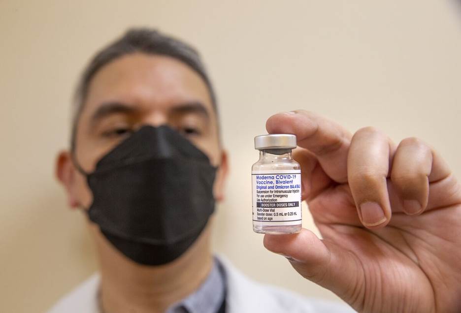 A pharmacist holds a bottle of the Moderna bivalent COVID-19 vaccine booster. 
