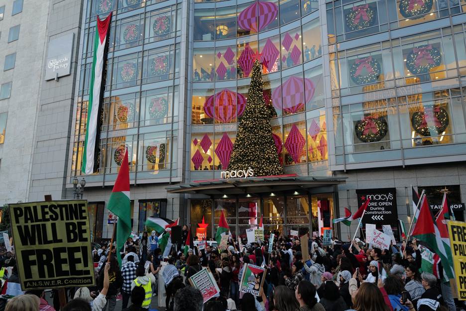 A group of people protesting in front of a building  Description automatically generated