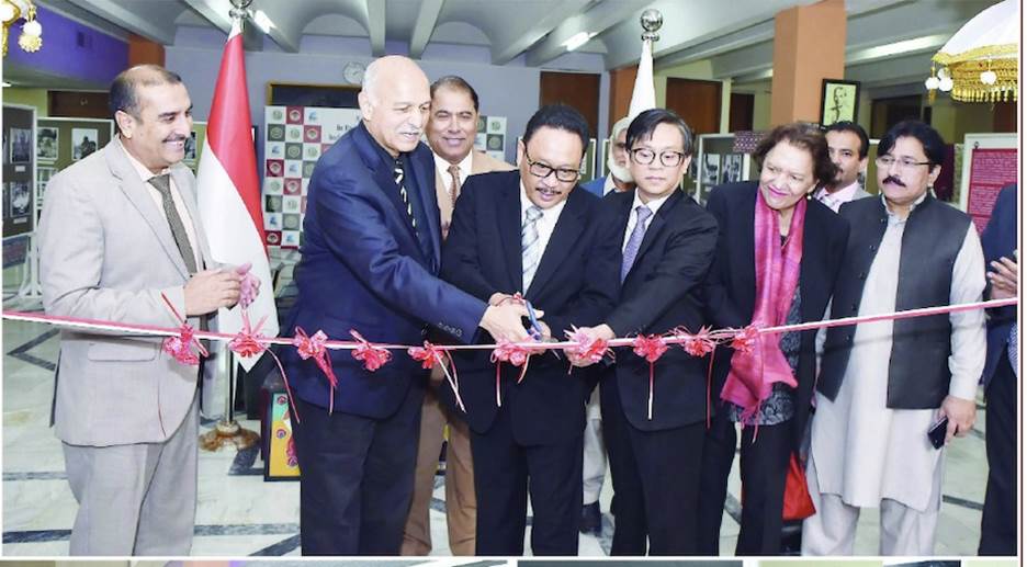 A group of people cutting a ribbon Description automatically generated