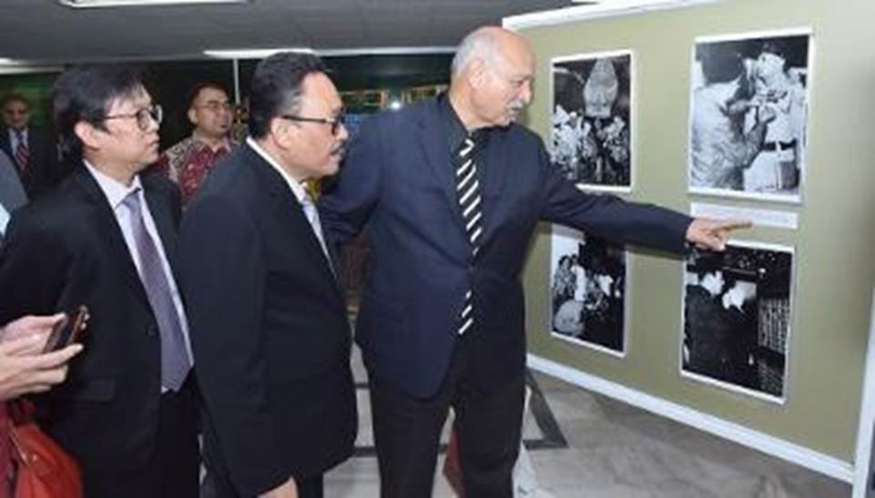 A group of men looking at a display  Description automatically generated