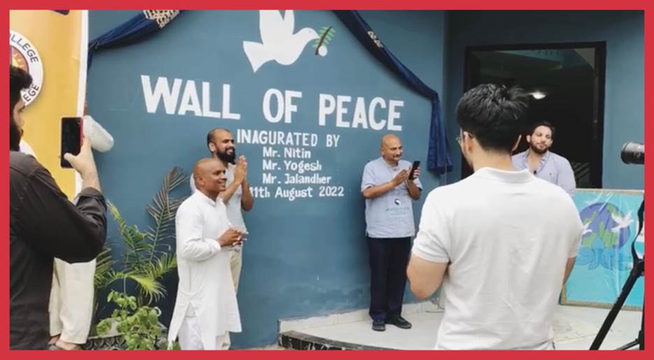 A group of men standing in front of a blue wall  Description automatically generated