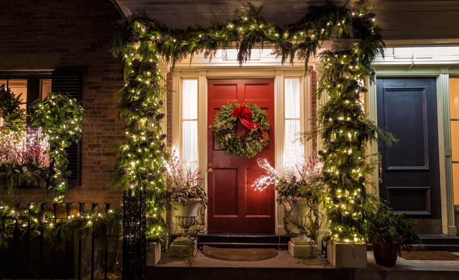 A red door with a wreath and lights on it  Description automatically generated