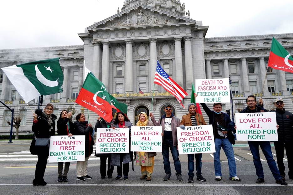 A group of people holding signs and flags in front of a building  Description automatically generated