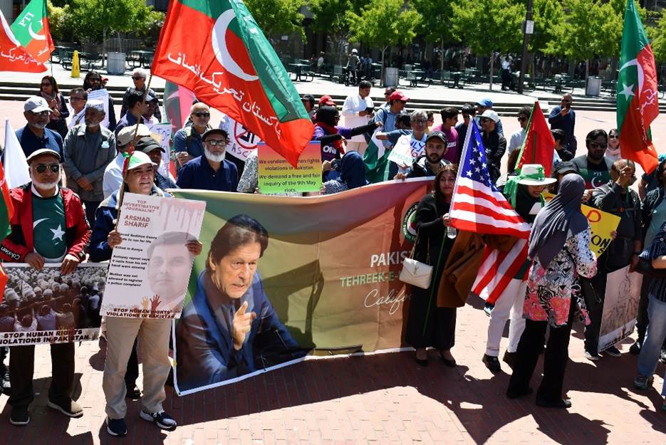 A group of people holding signs and flags Description automatically generated with low confidence