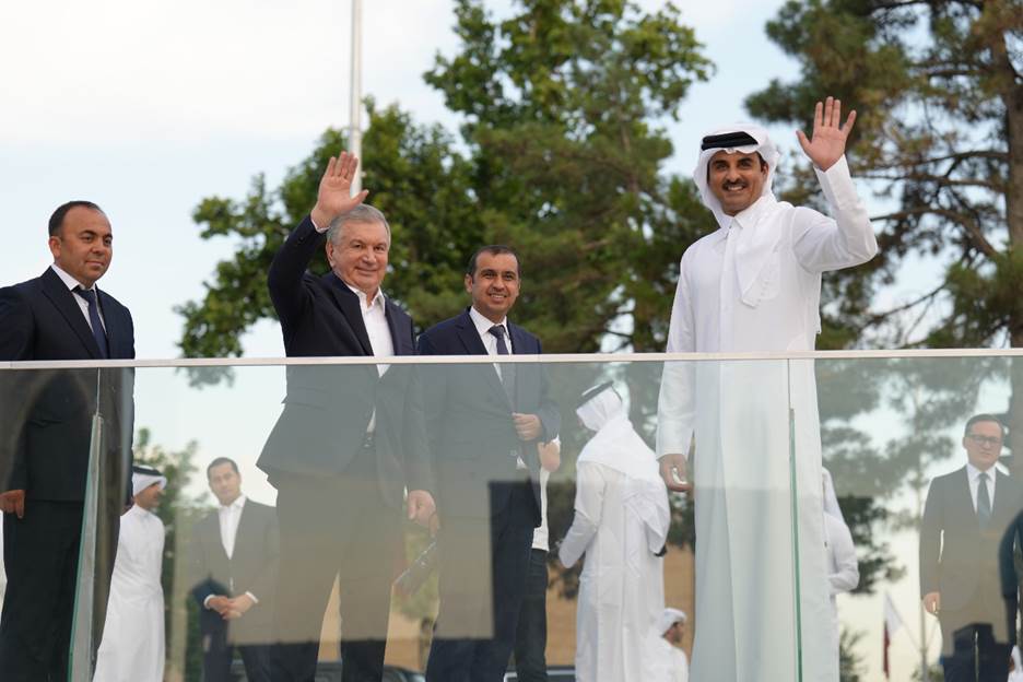 A group of men waving in front of a glass fence Description automatically generated with low confidence
