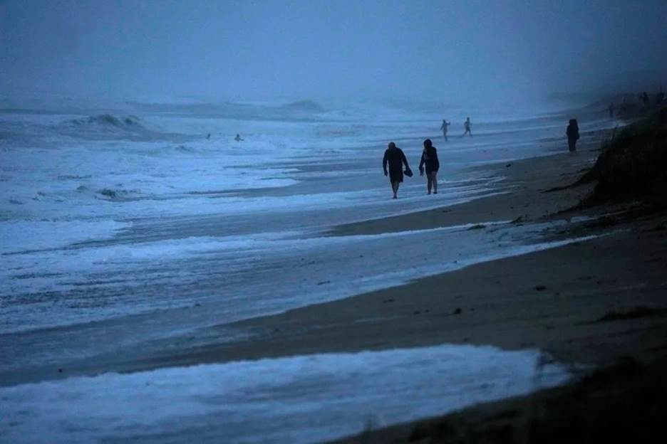 FILE - People walk along the oceanfront at Jensen Beach Park, where waves were reaching the dune's edge as conditions deteriorated with the approach of Hurricane Nicole, Nov. 9, 2022, in Jensen Beach, Fla. After months of gradually warming sea surface temperatures in the tropical Pacific Ocean, NOAA officially issued an El Nino advisory Thursday, June 8, 2023, and stated that this one might be different than the others. (AP Photo/Rebecca Blackwell, File)