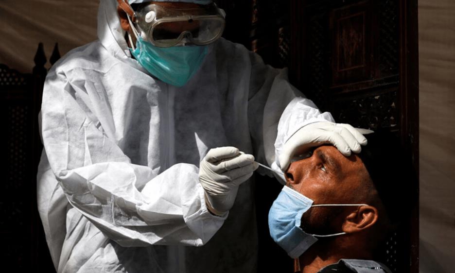 A paramedic wearing protective gear takes a nose-swab sample to be tested for the coronavirus in Karachi. — Reuters/File