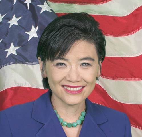 A person smiling in front of a flag Description automatically generated