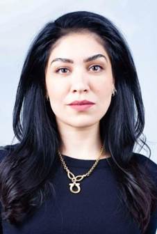 A person with long black hair wearing a gold necklace Description automatically generated with medium confidence