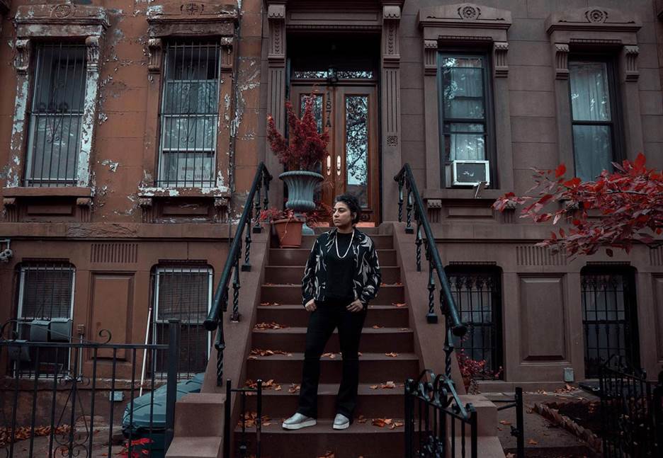 A person standing on a set of stairs in front of a building Description automatically generated with medium confidence