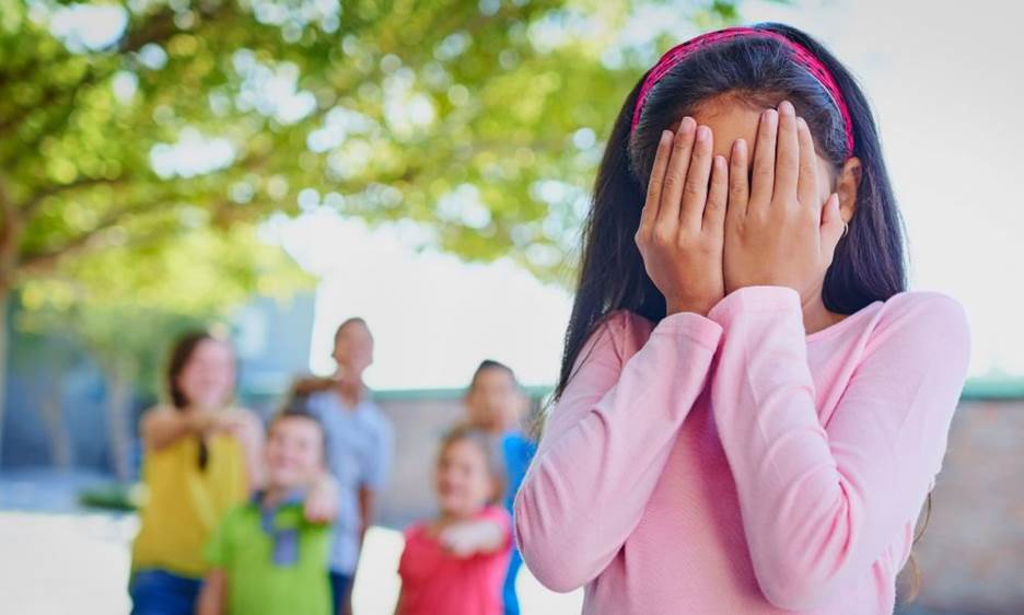A child covering her face with her hands Description automatically generated