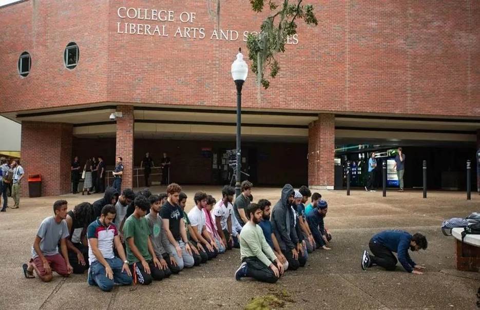 A group of people kneeling in front of a building  Description automatically generated