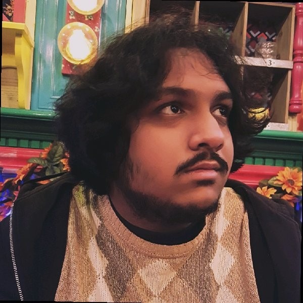 A person with long black hair and a mustache Description automatically generated