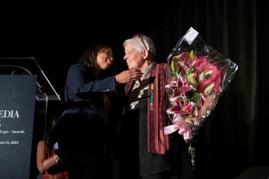 A person giving a bouquet of flowers to an old person Description automatically generated