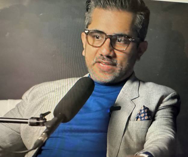 A person in a suit and glasses Description automatically generated